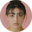 Portrait of a young woman with dark hair in a bun against a pink circular background.